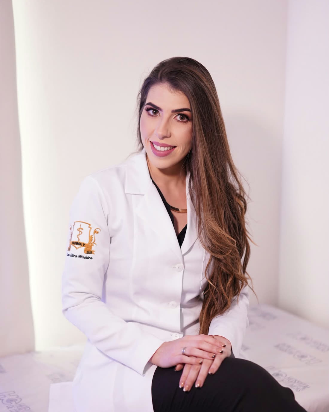 Dra. Adrine Betat em pé no consultório, de jaleco rosa